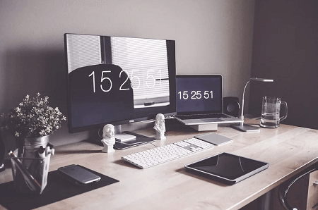 A desk with a computer , laptop , tablet , and keyboard.